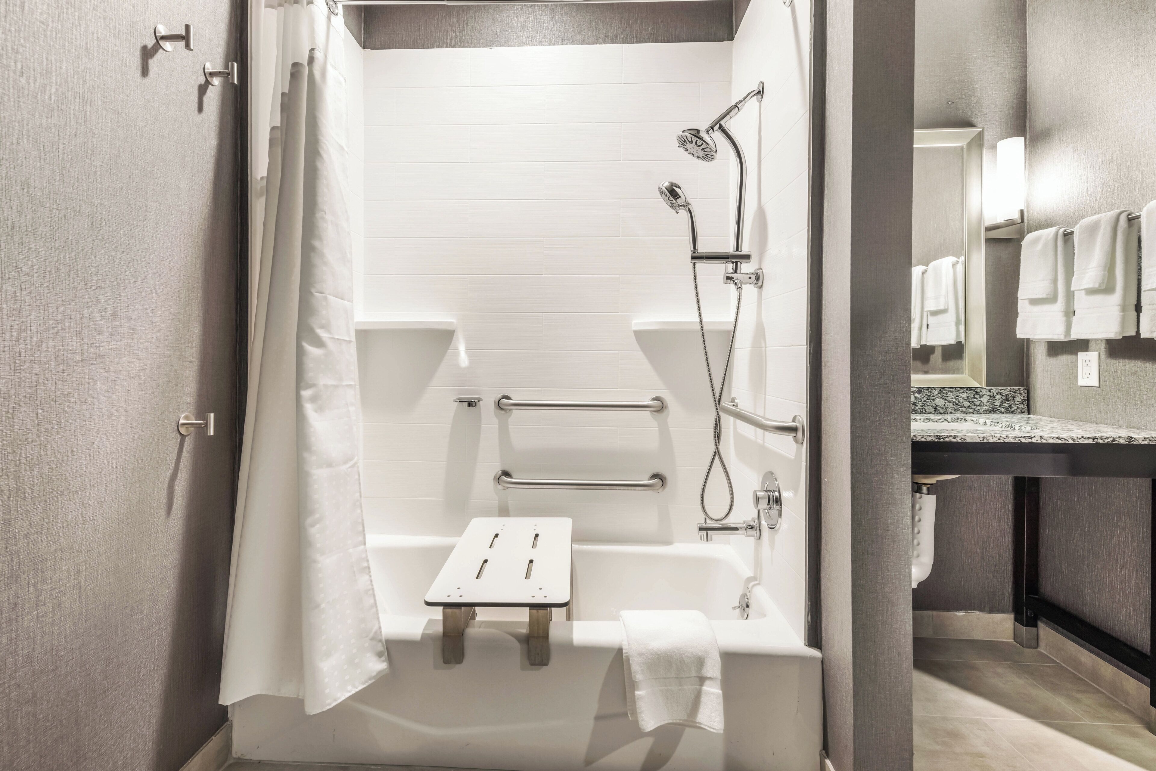 A modern bathroom with a shower, toilet, and a towel rack.