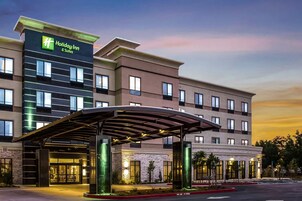 A Holiday Inn & Suites building with a covered entrance, multiple floors, and a landscaped front area.