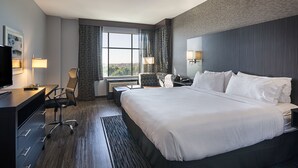 A hotel room with a large bed, a desk with a chair, a television, and a window with curtains. - Holiday Inn & Suites Silicon Valley - Milpitas by IHG (Milpitas)