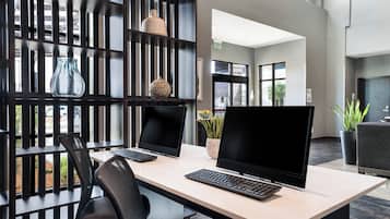 Un espacio de oficina moderno con dos escritorios, cada uno con un ordenador y teclado, una silla, y objetos decorativos en estanterías.