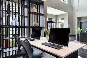 A modern office space with two desks, each with a computer and keyboard, a chair, and decorative items on shelves. - Holiday Inn & Suites Silicon Valley - Milpitas by IHG (Milpitas)