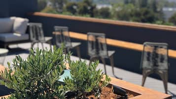 Terraza en la azotea con mobiliario exterior, incluyendo un sofá y sillas, además de un jardín vertical con plantas verdes.