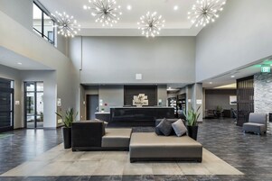 Un hall de hotel con mostrador de recepción, zona de estar y señalización de salidas.