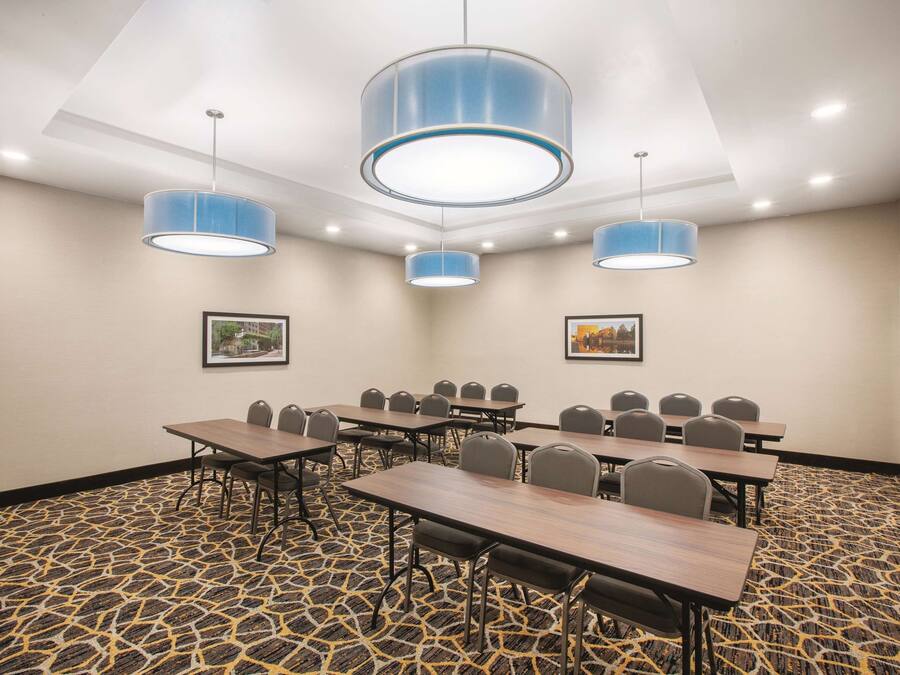 A conference room with tables and chairs, blue pendant lights, patterned carpet, and framed pictures on the walls.