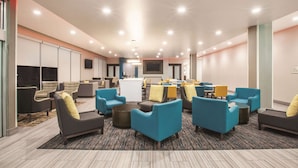 A modern hotel lobby with multiple seating areas, a reception desk, and a TV screen. - La Quinta Inn & Suites by Wyndham Tulsa Broken Arrow (Broken Arrow)