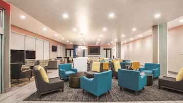 Relax in the hotel lobby's central seating area, featuring comfortable armchairs and sofas, a bar with stools, and a flat-screen TV.