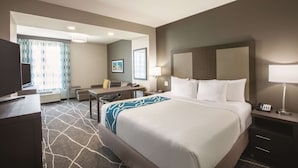 A hotel room with a large bed, a desk, a chair, a TV, and a window with curtains. - La Quinta Inn & Suites by Wyndham Tulsa Broken Arrow (Broken Arrow)