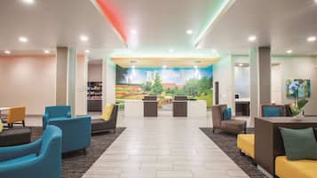 A modern lobby with a reception desk, seating area, and a mural of a cityscape.