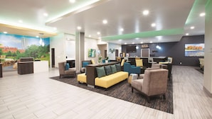 A modern lobby with a reception desk, seating area, and a bar. - La Quinta Inn & Suites by Wyndham Tulsa Broken Arrow (Broken Arrow)