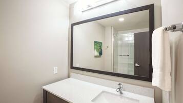 A bathroom with a large mirror, a white sink, and a towel hanging on the wall.