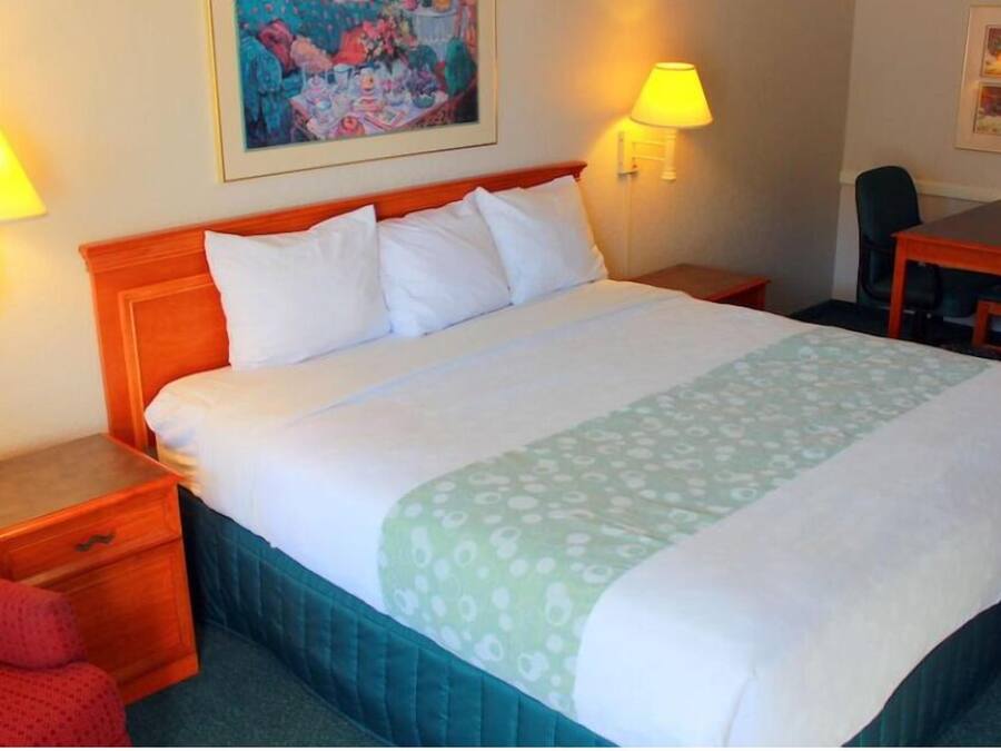 A hotel room with a large bed, two bedside tables, a desk, and chairs.