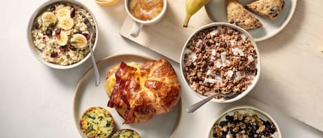 A breakfast spread with various dishes including oatmeal, coffee, a croissant, and a banana.