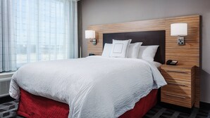 A hotel room with a large bed, two bedside tables, a nightstand, and a window with curtains. - TownePlace Suites by Marriott Austin Parmer/Tech Ridge (Austin)