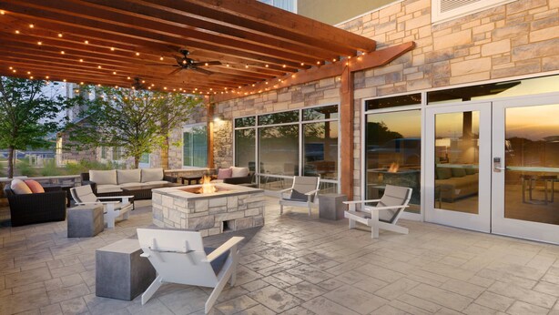 An outdoor patio with stone flooring, a fire pit, and various seating arrangements. - TownePlace Suites by Marriott Austin Parmer/Tech Ridge (Austin)