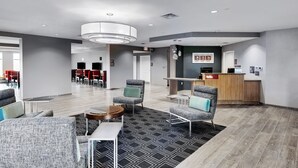 A modern lobby with a reception desk, seating area, and a large window. - TownePlace Suites by Marriott Austin Parmer/Tech Ridge (Austin)