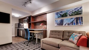 A compact hotel room with a kitchenette, a sofa, a desk, and a TV. - TownePlace Suites by Marriott Austin Parmer/Tech Ridge (Austin)