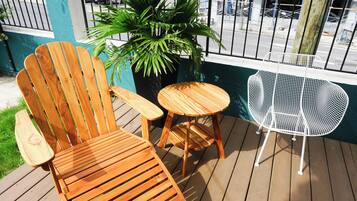 A wooden deck with a wooden chair, a small round table, and a white metal chair.