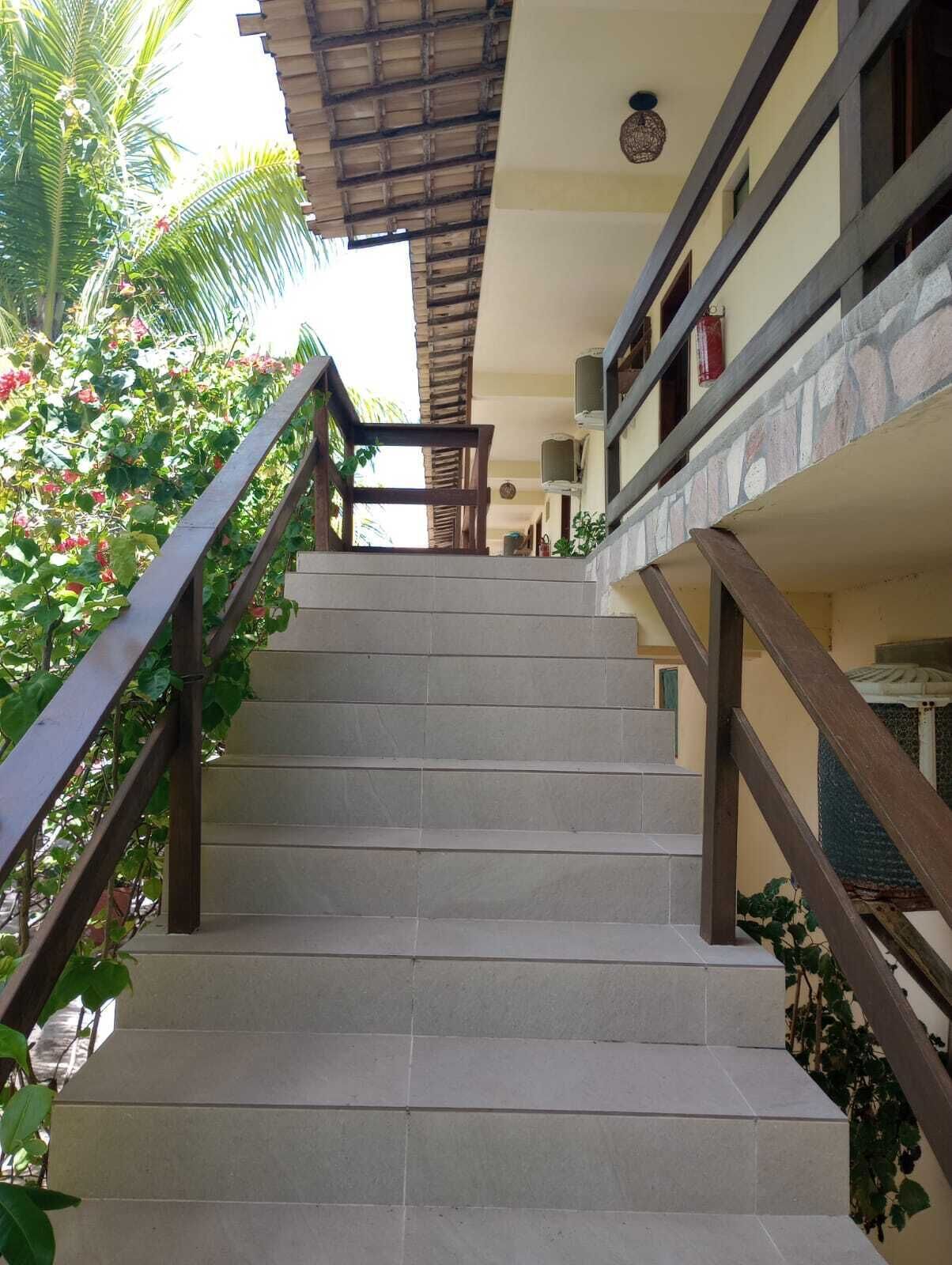 Una escalera con barandilla de madera que conduce a una zona cubierta con vistas a un edificio.