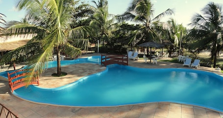 Una piscina al aire libre, sombrillas, sillones reclinables de piscina