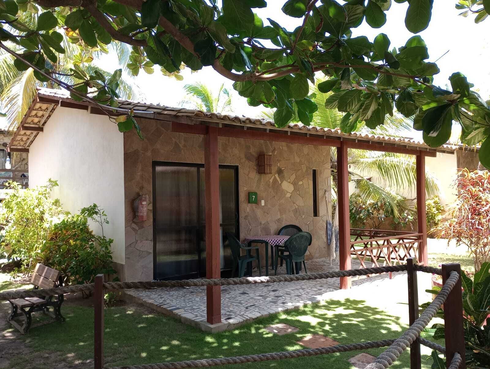 Un petit bâtiment rustique à la façade en pierre, doté d’un patio couvert avec des sièges en plein air, et sur lequel on peut voir le chiffre « 7 » peint sur le mur.