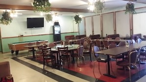 A dining area with multiple tables and chairs, a pool table, and hanging plants. - Tahitian Motor Inn (Pasco)