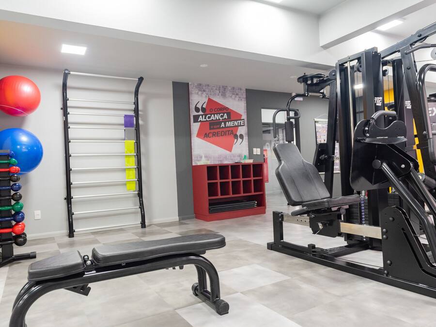 A gym with exercise equipment, a bench, and a wall with motivational text.