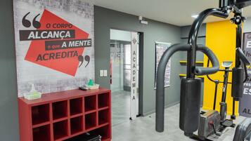 A gym with exercise equipment, a red shelf with items, and a motivational quote on the wall.