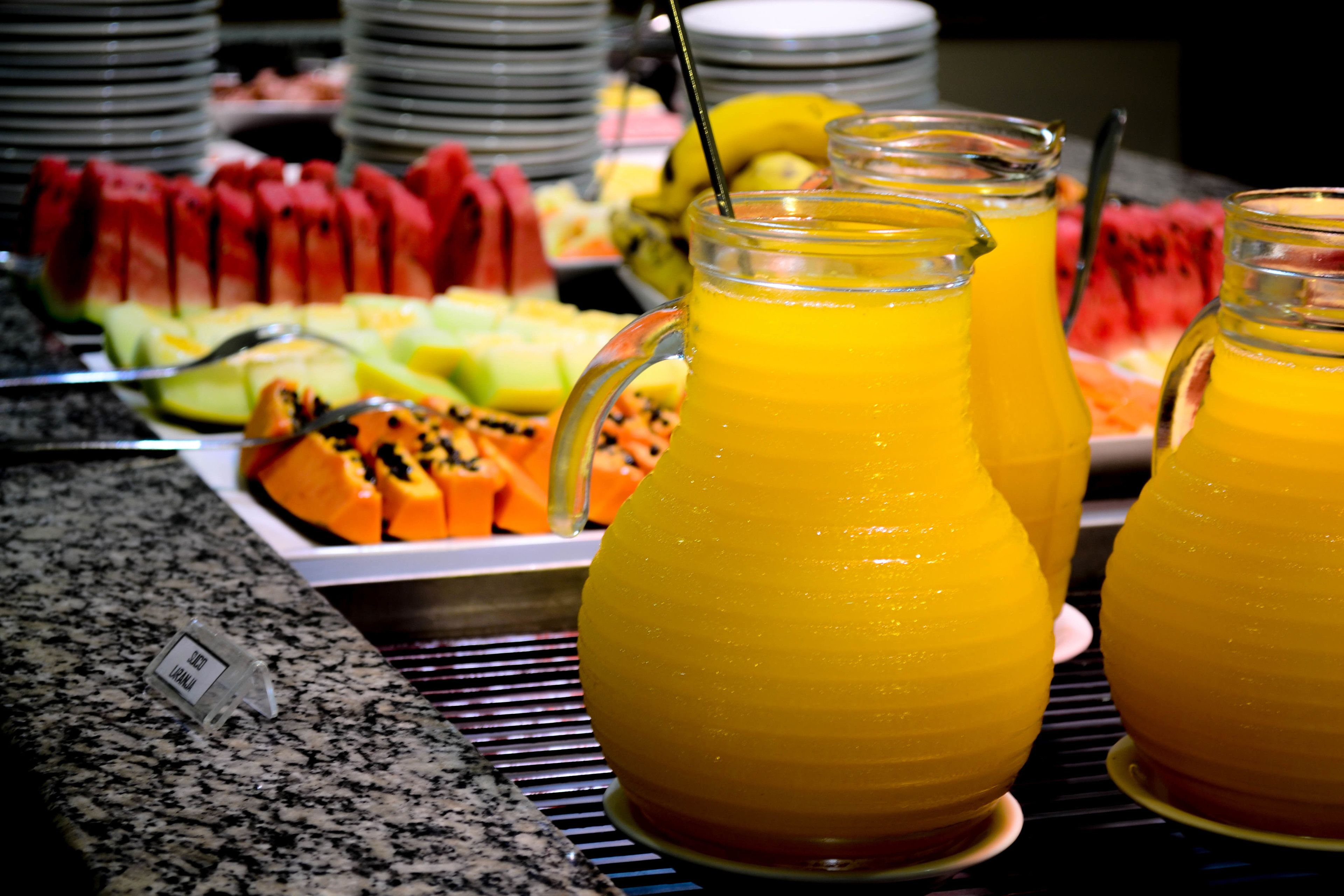 A buffet with various fruits and a pitcher of orange juice.