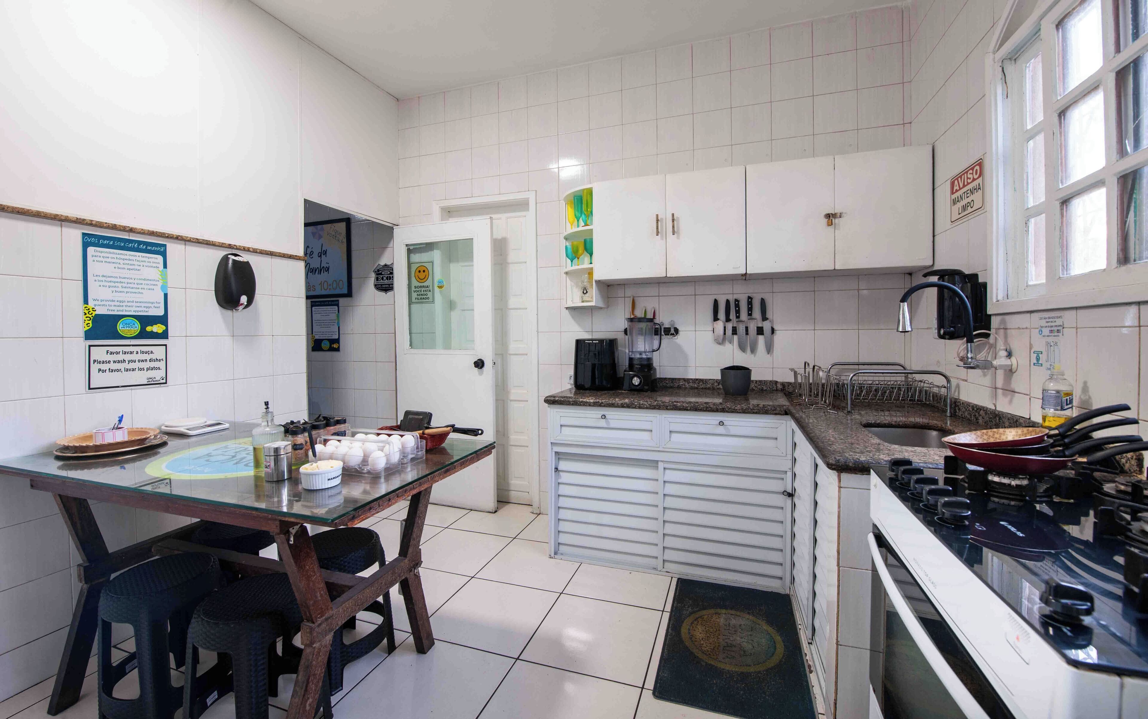 Una cocina con armarios blancos, estufa, pileta y distintos utensilios.