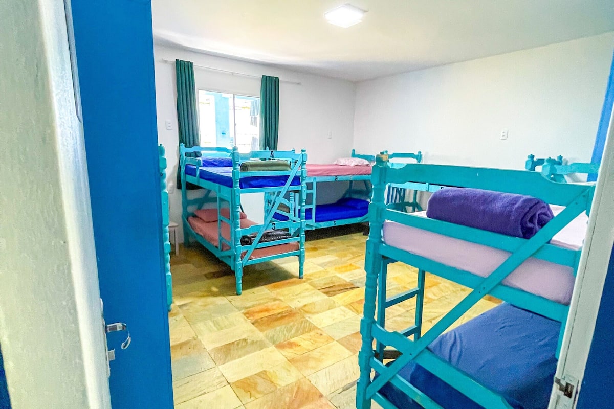 Une chambre de dortoir avec des lits superposés, un sol carrelé et une porte donnant sur une autre pièce.