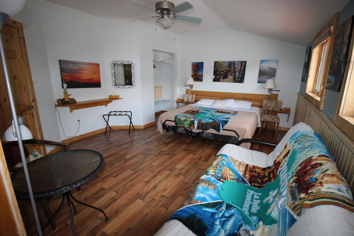 Une chambre d’hôtel avec un lit, un canapé, une petite table et un ventilateur de plafond.