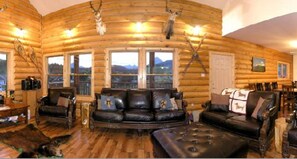 A log cabin interior with a leather sofa, wooden flooring, and deer antlers on the walls. - York Creek Bed and Breakfast (Coleman)