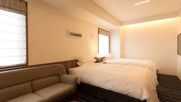 Una habitación de hotel con cama, sofá, una mesita y ventana con persianas.