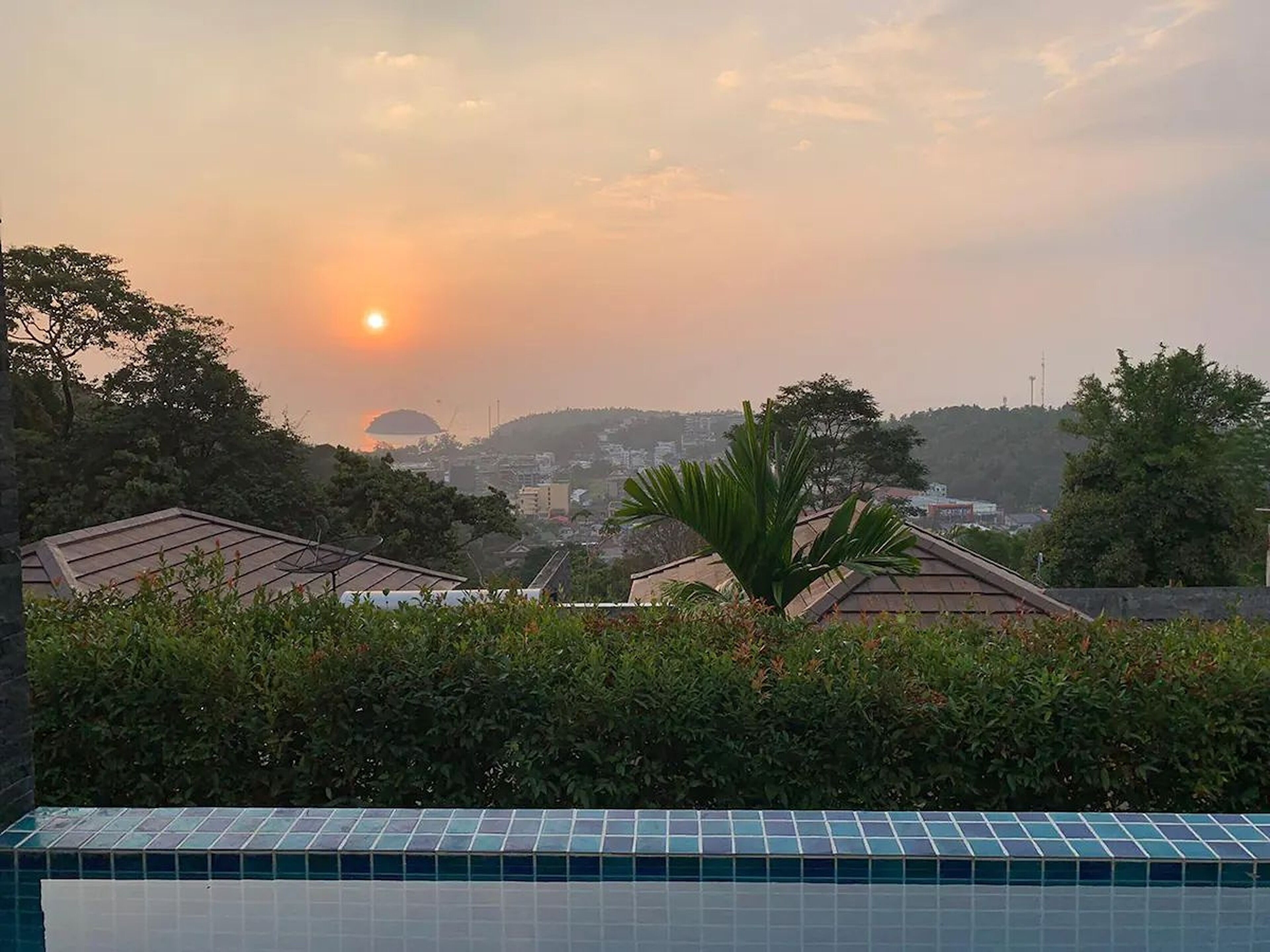 A residential area with a swimming pool, houses, and a sunset view.