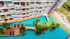 Un hôtel à plusieurs étages doté d’une piscine sur le toit, avec des chaises longues et des palmiers.