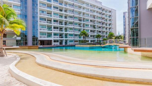 Un hôtel moderne doté de nombreux balcons, d’une piscine et de palmiers.