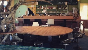 Un espace bar avec une table et des chaises en bois, entouré d’étagères remplies de bouteilles et de collations.