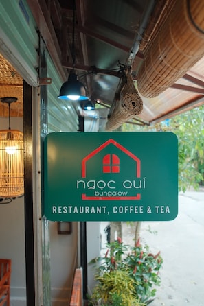 A green sign for ngoc qui bungalow restaurant, coffee, and tea. - Ngoc Qui Bungalow (Phu Quoc)