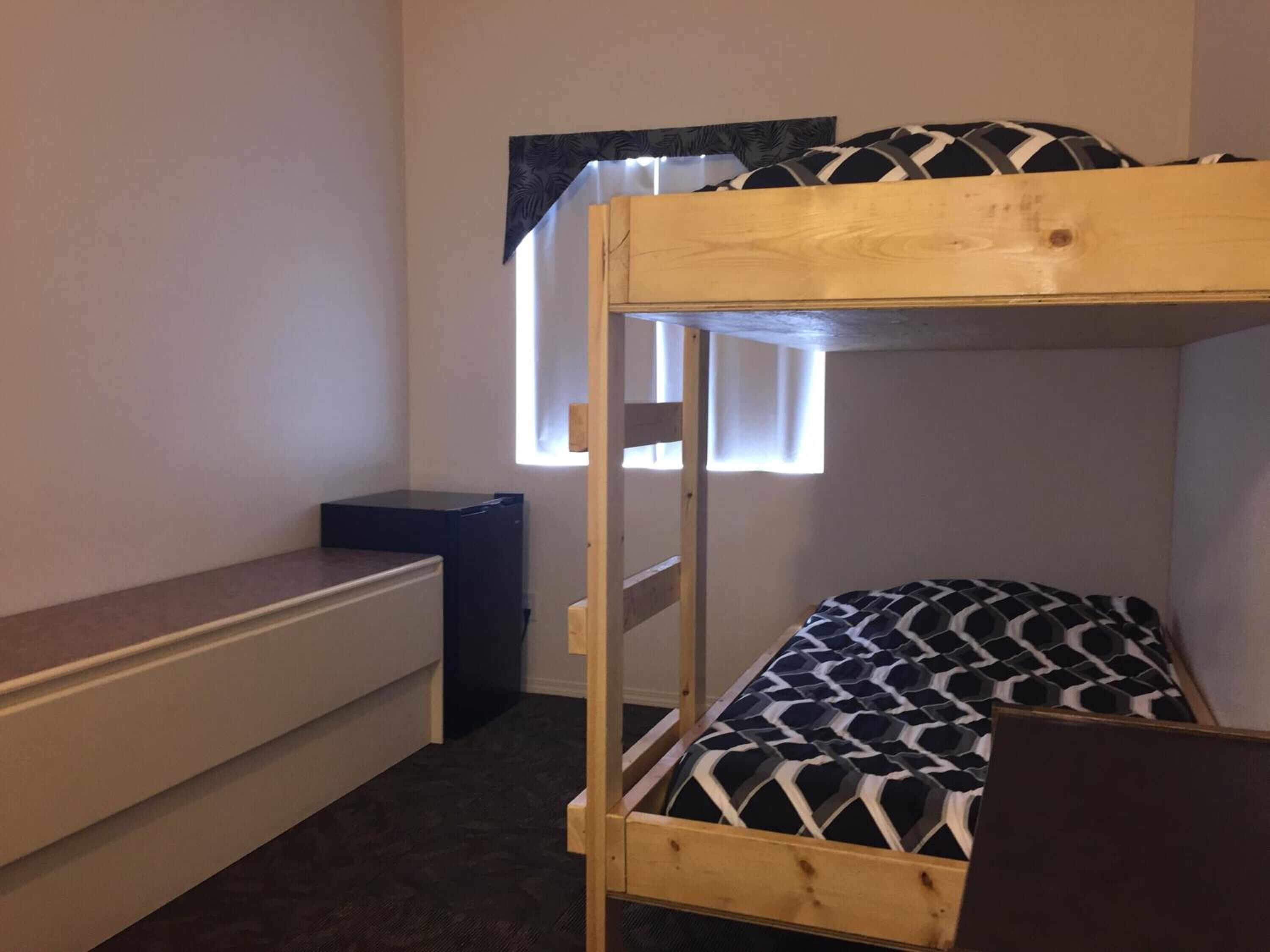 A bunk bed with a patterned mattress, a small desk, and a radiator.