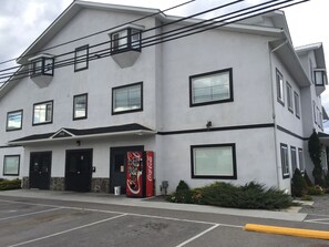 A two-story building with a flat roof, multiple windows, and a Coca-Cola vending machine. - Invermere Hostel (Invermere)