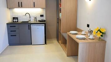 Una cocina moderna con armarios grises, lavavajillas y encimera de madera con cafetera y platos.