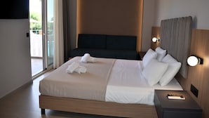 Una habitación de hotel moderna con una cama grande, un televisor de pantalla plana montado en la pared y un ventanal corredero que da a un balcón.