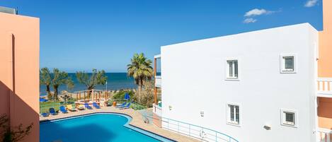 A swimming pool with lounge chairs and a view of the sea.