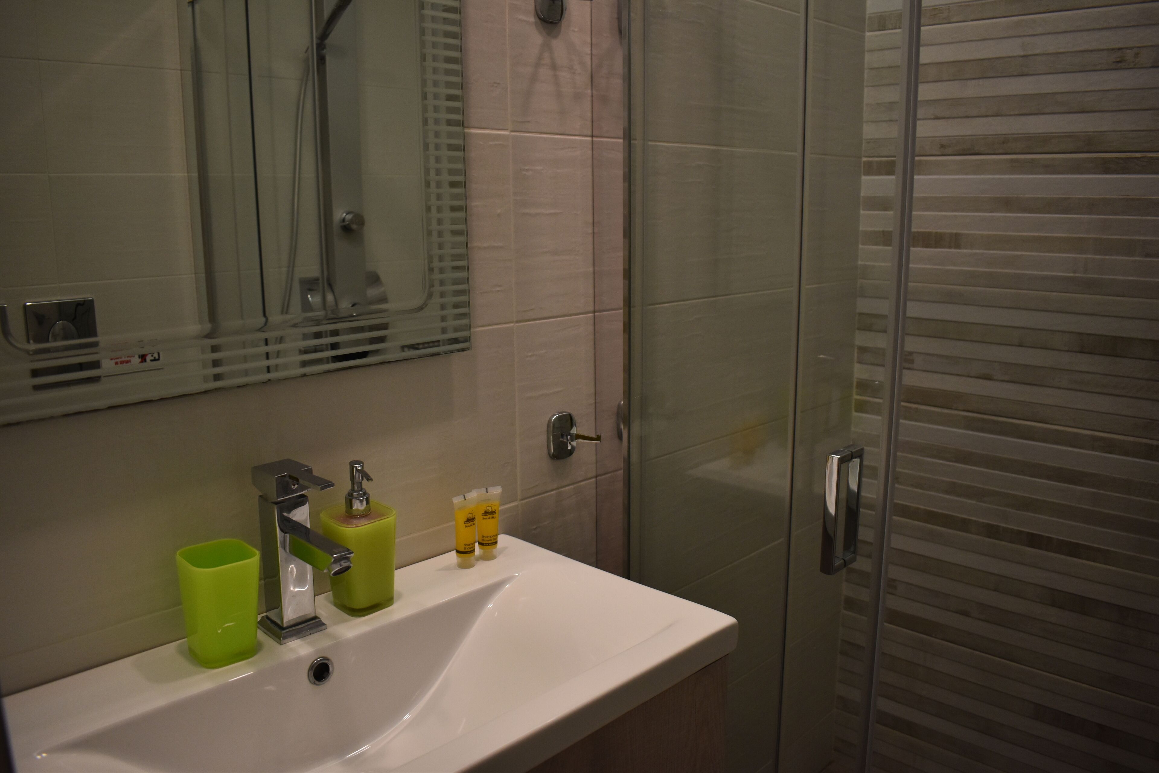 Un baño con lavamanos, espejo y cabina de ducha de vidrio.