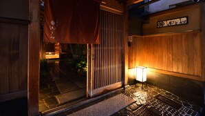 A traditional Japanese entrance with a wooden sliding door, a stone pathway, and a lit lantern. - Muromachi Yutone Kyokoyado (Kyoto)