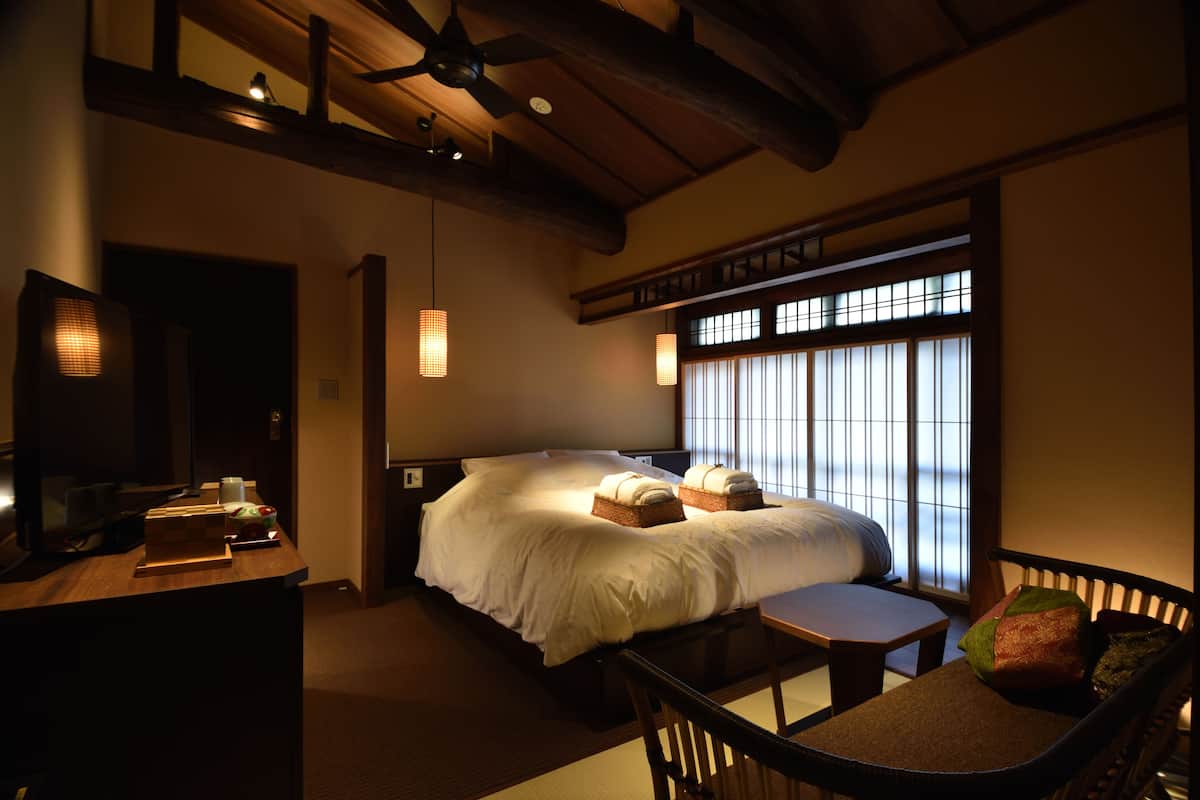 A traditional Japanese-style bedroom with a bed, bedside table, and a small seating area.