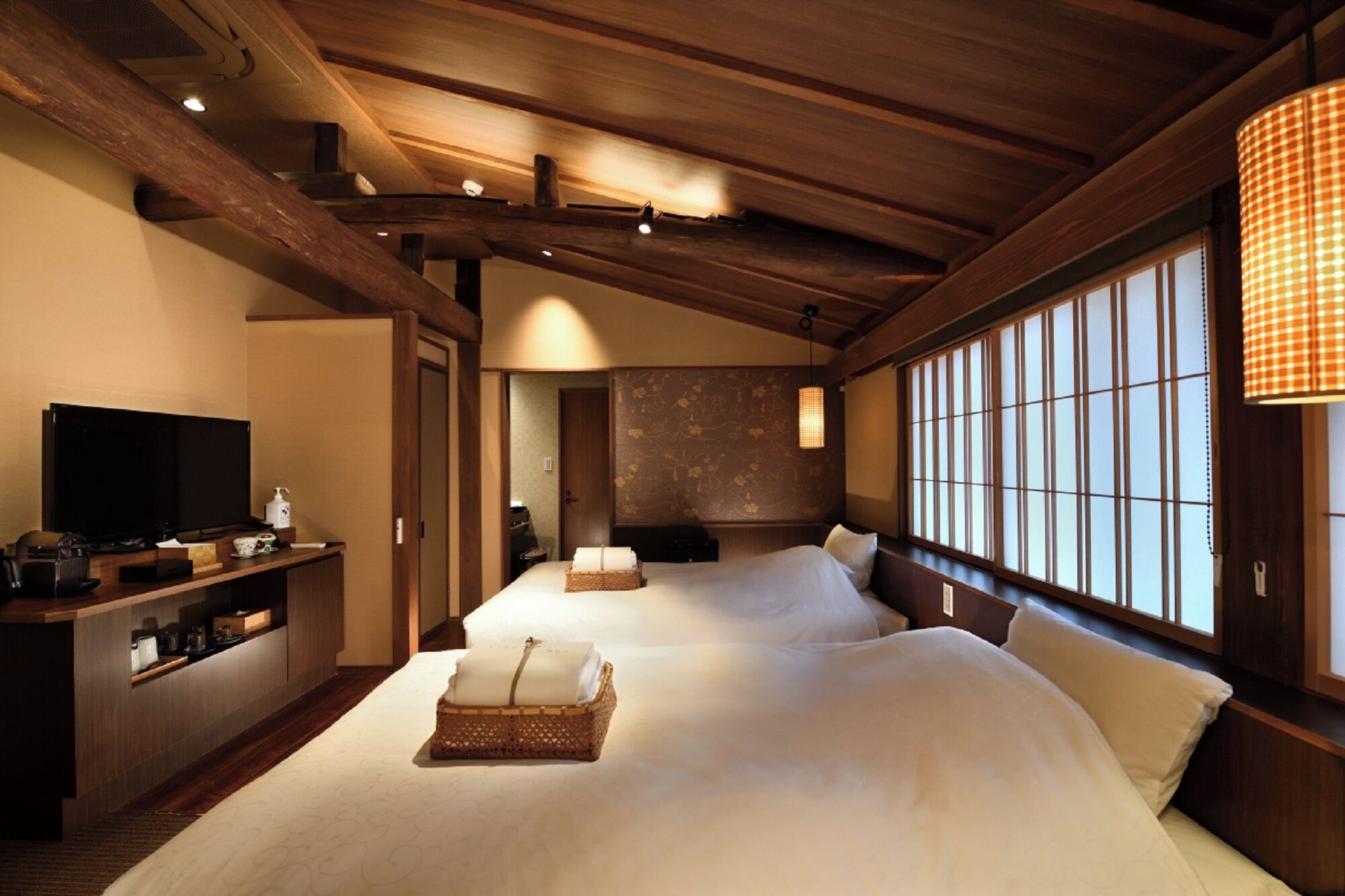 A hotel room with a large bed, a television, a desk with a computer, and a window with a view.