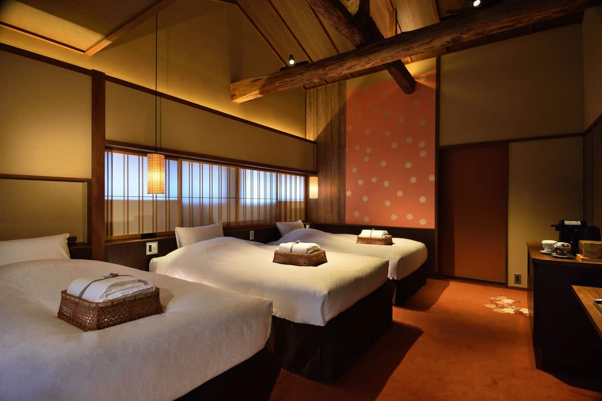 A hotel room with two beds, a wooden ceiling, and a polka dot wall.