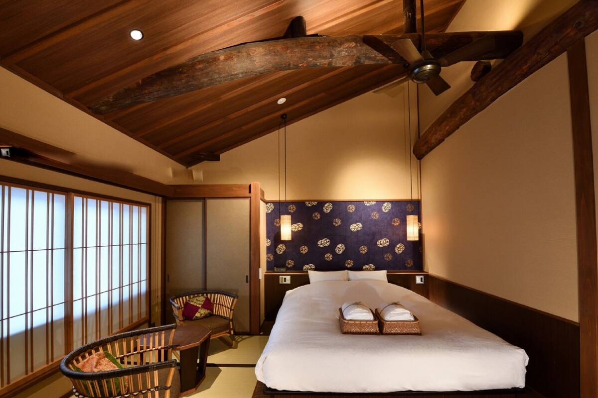 A traditional Japanese-style room with tatami flooring, a low wooden bed, a ceiling fan, and a shoji screen.