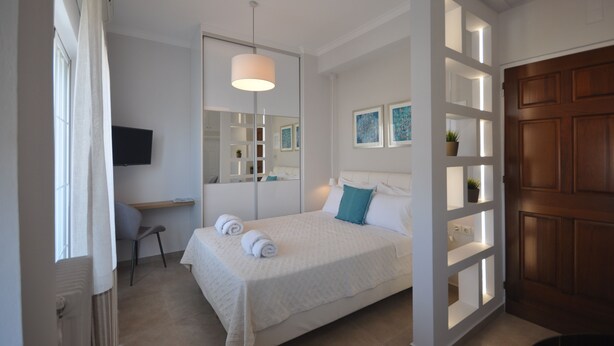Ein Schlafzimmer mit Bett, Schreibtisch, Stuhl, Fernseher und einer Tür mit Holzverkleidung.